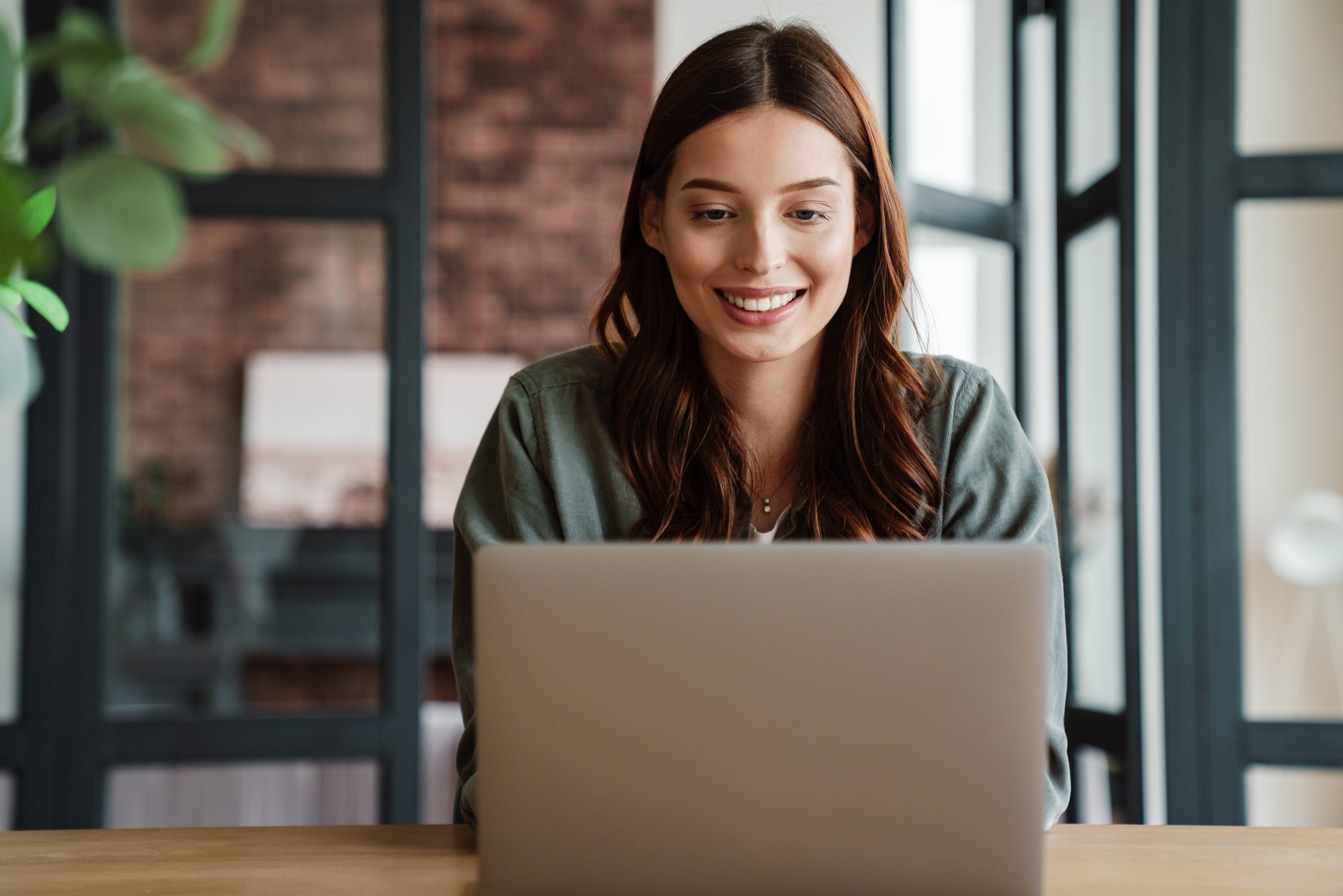 Beautiful smiling woman working with laptop while sitting at table